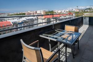 d'une table et de chaises en verre sur un balcon avec vue. dans l'établissement AC Hotel A Coruña by Marriott, à La Corogne