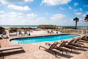 a swimming pool with lounge chairs and the beach at Courtyard by Marriott Fort Walton Beach-West Destin in Fort Walton Beach