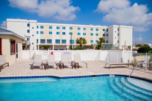 a hotel with a pool and chairs and a building at Courtyard by Marriott Fort Walton Beach-West Destin in Fort Walton Beach