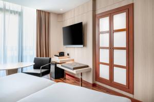 a hotel room with a bed and a desk and a tv at AC Hotel Gran Canaria by Marriott in Las Palmas de Gran Canaria