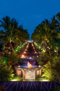a garden with a fountain and palm trees at night at The St. Regis Bali Resort in Nusa Dua