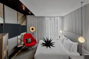a bedroom with a white bed and a red chair at W London in London