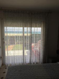 a bedroom with a large window with white curtains at Valentina Platja in Sant Antoni de Calonge