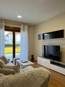 Una sala de estar con un sofá y un televisor de pantalla plana. en Costa Santander. Apartamento con jardín, en Santander