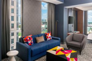a living room with a blue couch and a chair at Aloft Orlando Downtown in Orlando