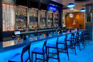 a bar with blue chairs and liquor bottles at Aloft Orlando Downtown in Orlando