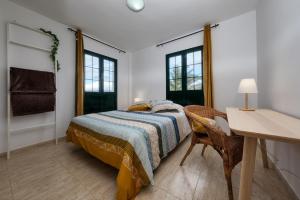 a bedroom with a bed and a desk and windows at Casa Gemma-quiet and relaxing place in Costa Teguise