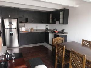 cocina con armarios negros y nevera de acero inoxidable en Cómodo conjunto residencial en la cuidad de Cuenca, en Cuenca