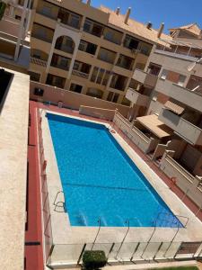 une grande piscine bleue en face d'un bâtiment dans l'établissement Coqueto y acogedor apartamento con piscina, à Roquetas de Mar