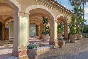 a row of arches with potted plants on a building at Hacienda Son Antem Golf Resort, Autograph Collection in Llucmajor