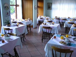 a dining room with tables and chairs with white table cloth at Albergo Riva in Reno Di Leggiuno