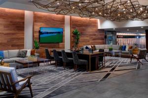 a lobby with a table and chairs and a tv at Kansas City Airport Marriott in Kansas City