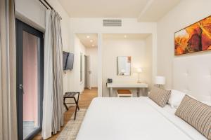 a white bedroom with a bed and a desk at Sheraton Cascais Resort - Hotel & Residences in Cascais