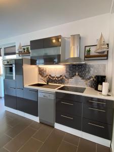 a kitchen with stainless steel appliances and black cabinets at Ferienwohnung "Seeperle" Marina Mücheln Geiseltalsee in Mücheln