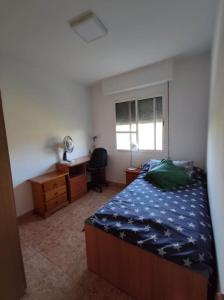 a bedroom with a bed and a desk and a window at Apartamento céntrico con vistas in Melilla