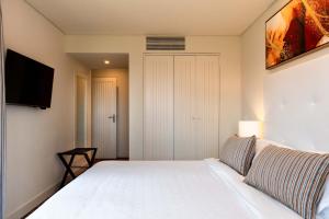 a bedroom with a white bed and a flat screen tv at Sheraton Cascais Resort - Hotel & Residences in Cascais