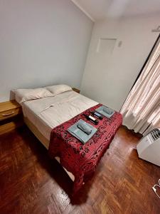Un pequeño dormitorio con una cama con una mesa roja en Vivi Mendoza en 
