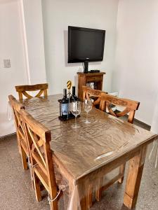 mesa de madera con 2 copas de vino y TV en Vivi Mendoza en 