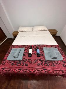 Barraquero的住宿－Vivi Mendoza，一张带红毯的床,上面有两部手机