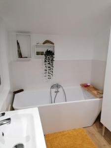 ein weißes Badezimmer mit einer Badewanne und einem Waschbecken in der Unterkunft maison bois in Ruaudin