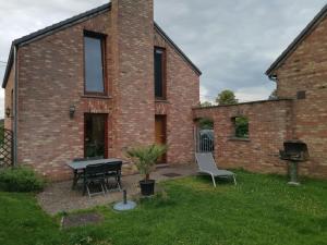 a brick house with a table and chairs in the yard at Gîte du Curnolo 3* pour 4/6pers avec spa, piscine in Namur