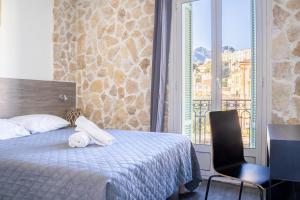 a bedroom with a bed and a chair and a window at Hotel De Belgique à Menton in Menton