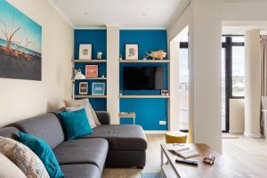 uma sala de estar com paredes azuis e um sofá em Stylish flat with balcony overlooking the sea em Costa da Caparica