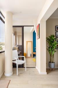 uma sala de estar com uma cadeira branca e uma mesa em Stylish flat with balcony overlooking the sea em Costa da Caparica mais 13 fotografias