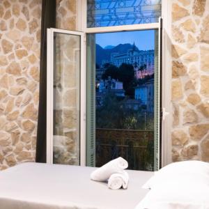 a bedroom with a window with a towel on the bed at Hotel De Belgique à Menton in Menton