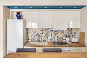 uma cozinha com armários brancos e uma geladeira em Stylish flat with balcony overlooking the sea em Costa da Caparica