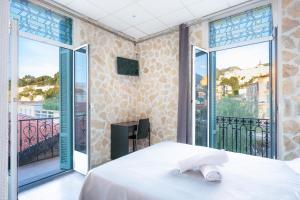 a bedroom with a bed and a balcony at Hotel De Belgique à Menton in Menton