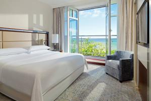 a bedroom with a bed and a chair and a large window at Sheraton Sopot Hotel in Sopot