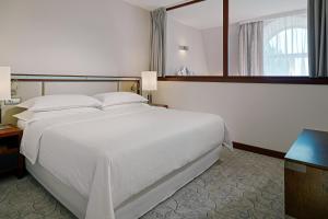 a hotel room with a large white bed and a mirror at Sheraton Sopot Hotel in Sopot