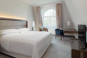 a bedroom with a large white bed and a desk at Sheraton Sopot Hotel in Sopot