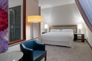 a bedroom with a bed and a chair and a shower at Sheraton Sopot Hotel in Sopot