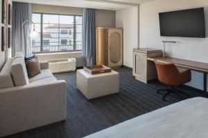 a hotel room with a couch and a desk and a television at Courtyard by Marriott Santa Cruz in Santa Cruz