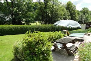 einem Picknicktisch und einem Sonnenschirm im Garten in der Unterkunft Gîte 295 Montagnes du Jura avec Spa et Sauna classé 3 étoiles in Foncine-le-Haut