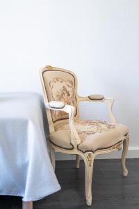 a chair is sitting next to a bed at Hotel De Belgique à Menton in Menton
