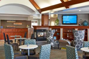 a lobby with tables and chairs and a fireplace at Residence Inn Minneapolis St. Paul/Roseville in Roseville