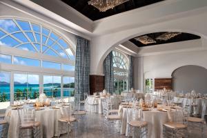 a ballroom with white tables and chairs and large windows at The Ritz-Carlton St. Thomas in Nazareth