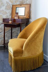 une chaise jaune avec une table et un miroir dans l'établissement Hotel De Belgique à Menton, à Menton