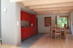 una cocina con armarios rojos y una mesa con sillas. en Maiensäss La Scera Val Poschiavo, 