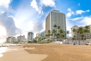 una spiaggia con un edificio alto e palme di San Juan Marriott Resort and Stellaris Casino a San Juan