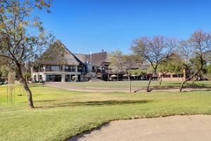 una casa su un campo da golf con alberi in primo piano di Zebula Golf Estate and Spa - Zebula Golfers Lodge a Mabula