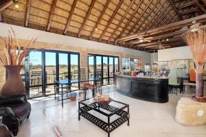 una sala de estar con bar, mesas y ventanas en Zebula Golf Estate and Spa - Zebula Golfers Lodge, en Mabula