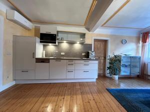 a kitchen with white cabinets and a wooden floor at Boarding House Obernburg in Obernburg am Main