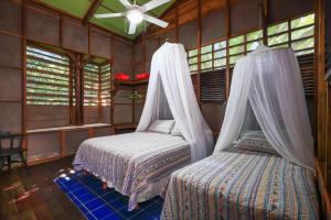 a bedroom with two beds and a ceiling fan at La Kukula Lodge in Puerto Viejo