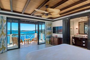 Scrub Island Resort, Spa & Marina في The Mill: غرفة نوم بسرير ومروحة سقف