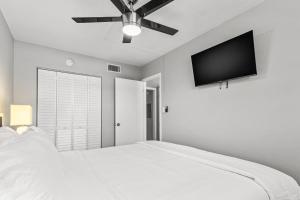 a bedroom with a white bed and a flat screen tv at Sunset Beach Suites in St Pete Beach