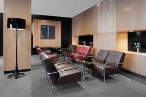 ヒホンにあるAC Hotel Gijón by Marriottの革張りの椅子とバーが備わる待合室